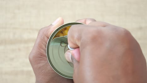 persona abriendo una lata de maíz