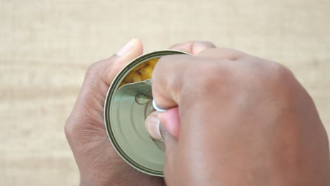 person opening a can of corn