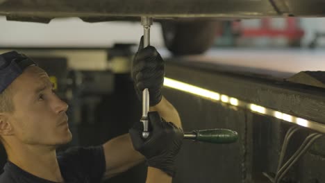 auto mechanic working underneath car lifting machine at the garage. auto repair shop, car service, repair.