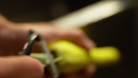 closeup view of peeling of radish skin using a manual peeler.