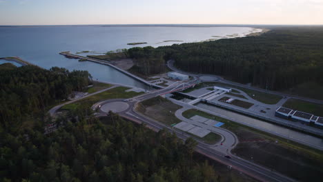 Aerial-view-of-Vistula-Spit-Canal-with-Baltic-Sea-and-green-FOrest-landscape-in-background-at-sunset---Connection-between-Gdansk-Bay-and-Vistula-Lagoon-in-Poland