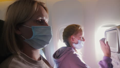 A-woman-with-a-child-fly-on-an-airplane,-they-are-wearing-protective-masks.-Tired-of-the-tegel-flight