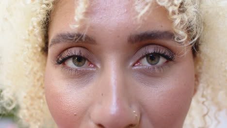 close-up of a young biracial woman with curly blonde hair and a nose ring