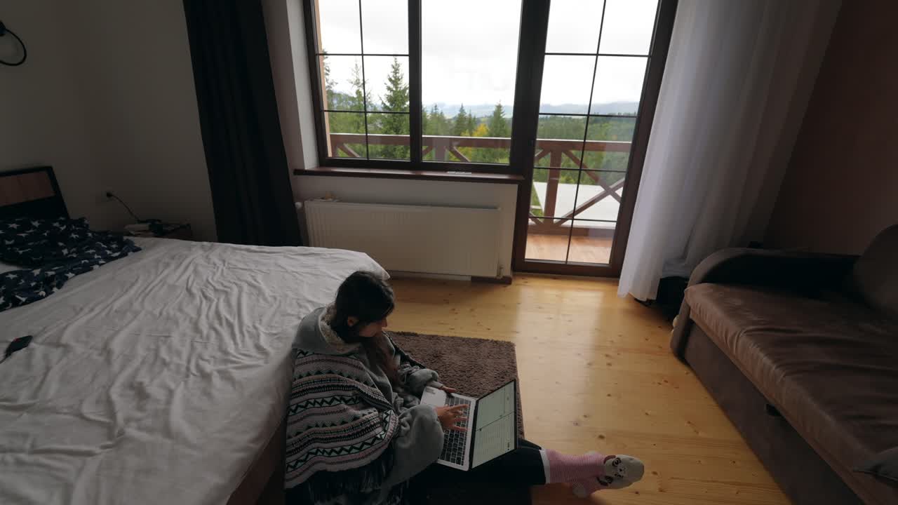 산을 볼 수 있는 편안한 침실에서 노트북을 사용하는 여성