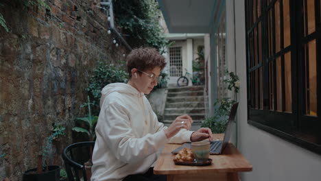 young woman working on laptop outside of a house