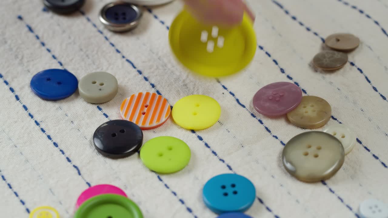 bottoni colorati che cadono su tessuto a righe in primo piano. abiti da sartoria e concetto di cucito professionale. scelta di accessori a bottoni per il materiale