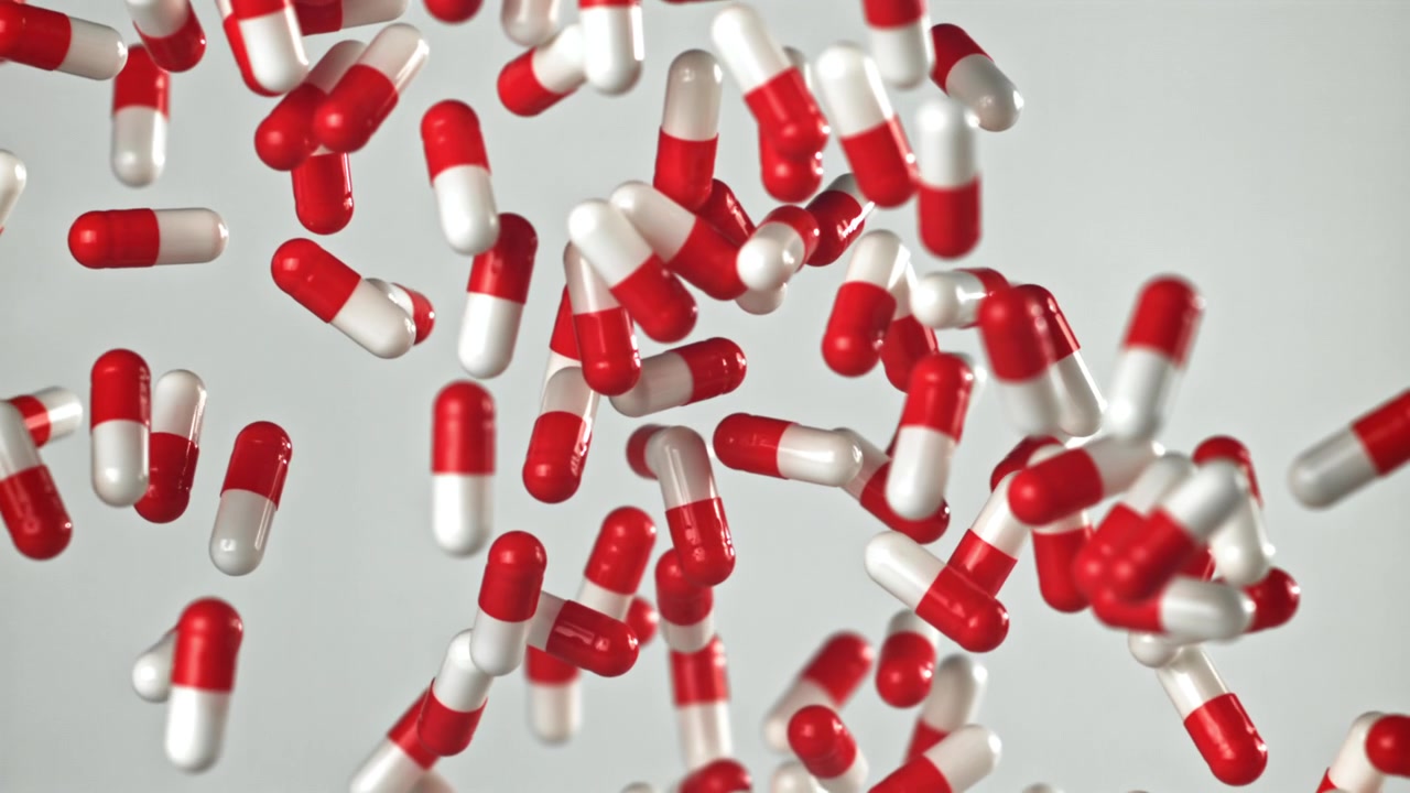 Capsule farmaceutiche rosse e bianche che cadono al rallentatore