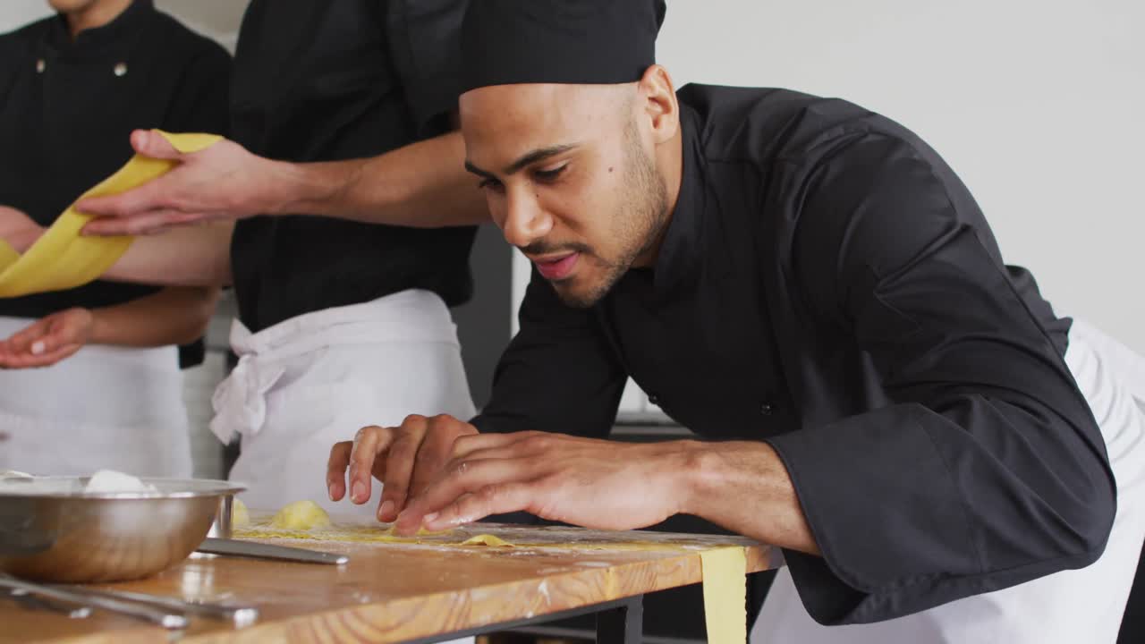 grupo diverso de chefs preparando platos y sonriendo en una cocina