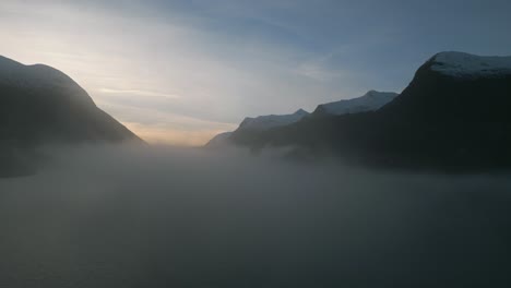 misty dawn breaks over oppstrynsvatnet lake in norway, mountains silhouetted