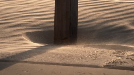 windswept sand around a wooden post