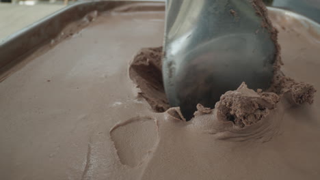 close-up slow motion shot of a spoon scooping a rich, creamy ball of chocolate ice cream. the luscious dark texture and smooth surface highlight the indulgent nature of this frozen dessert