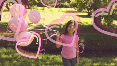 animation of pink hearts over smiling girl holding pink balloons in sunny park