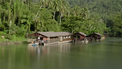 the loboc river in the philippines features houses built on its surface, nestled amidst lush coastal greenery