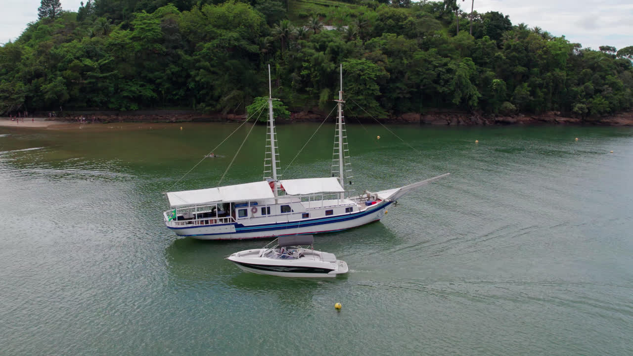 vista aérea dos barcos cruzando muy cerca en una hermosa playa tropical con bosque en el fondo