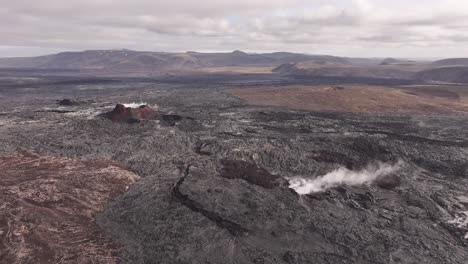iceland's volcanic landscape features rugged lava fields with steam rising from geothermal activity under a cloudy sky
