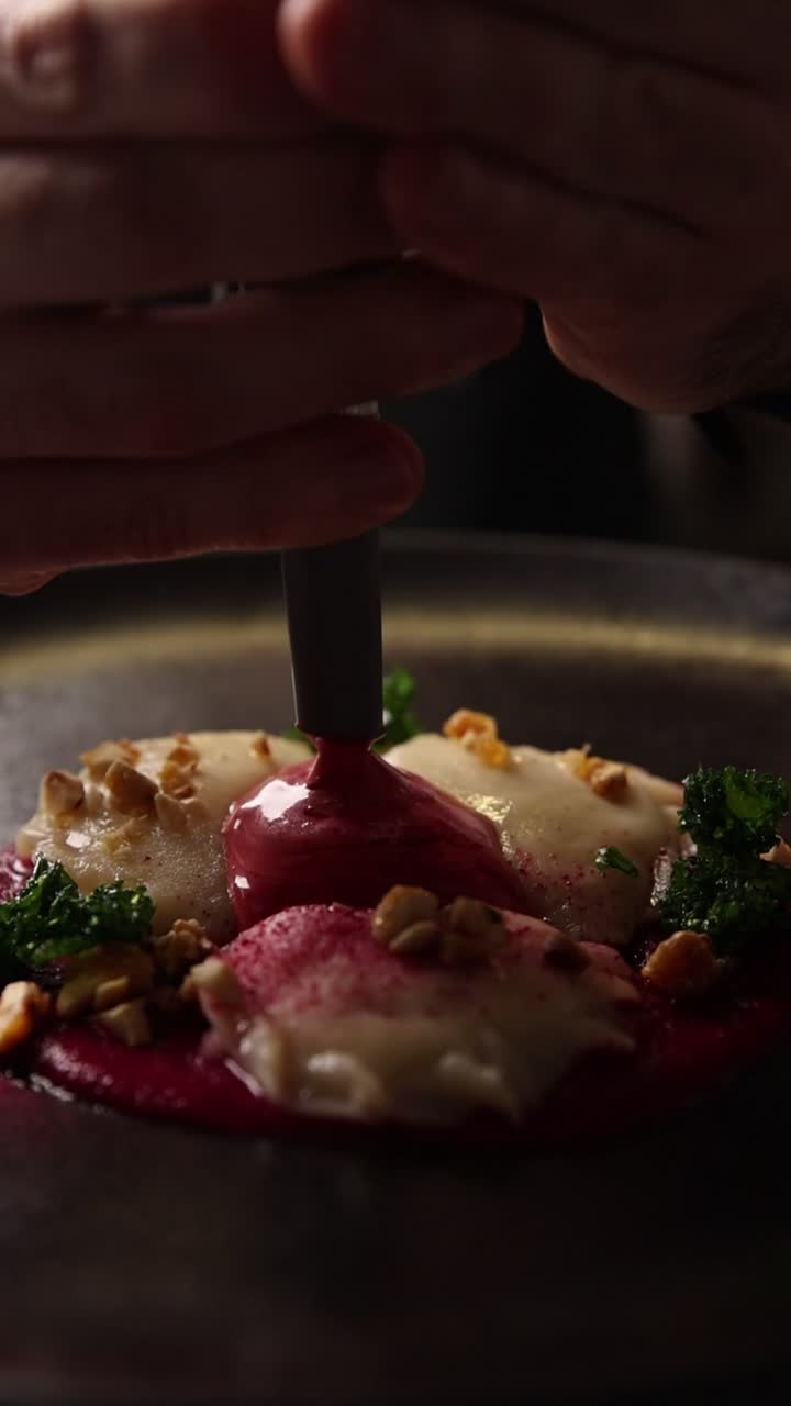 Chef's Hands Plating Gourmet Dumplings with Red Sauce and Garnish