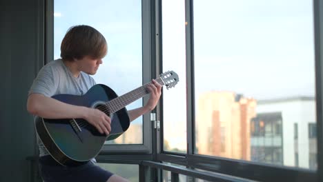 teenager playing guitar on balcony