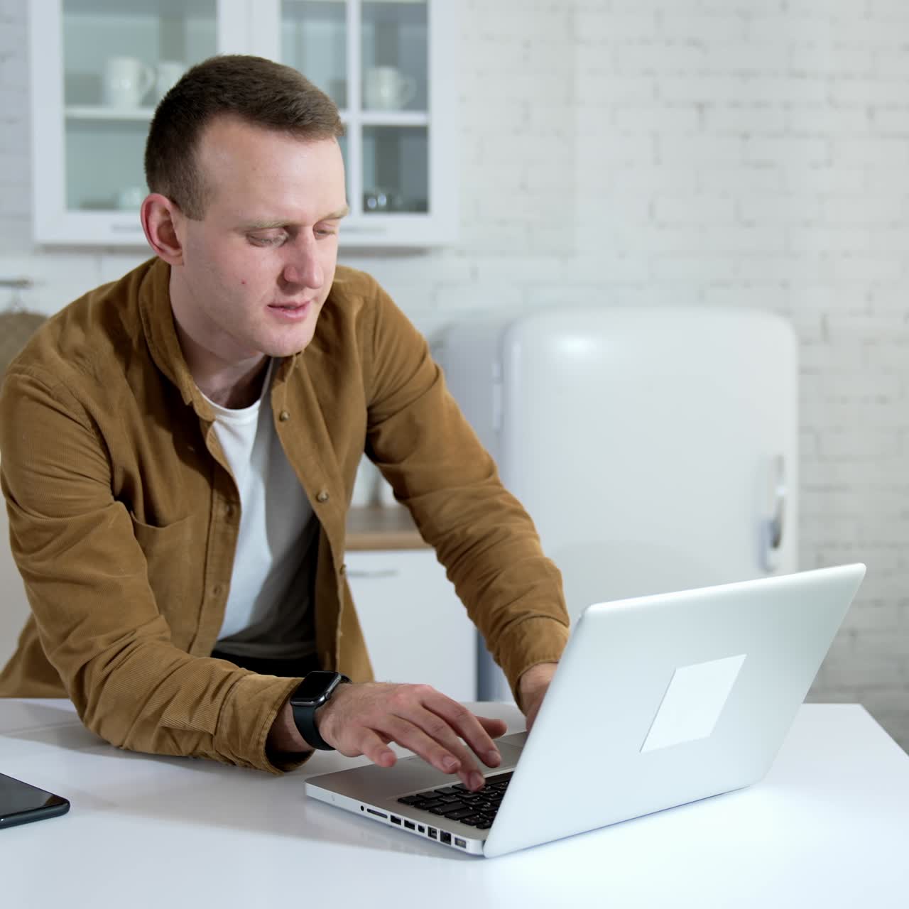 Young man speaking online. Freelancer male working with clients in front of a laptop. Student having a video call while sitting at home. Distant job