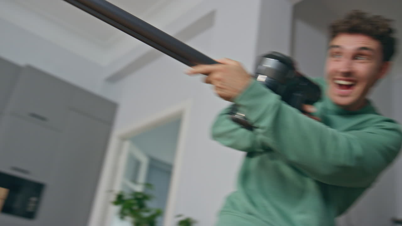 Joyful spouses fighting cleaning equipment at kitchen closeup. Pair having fun