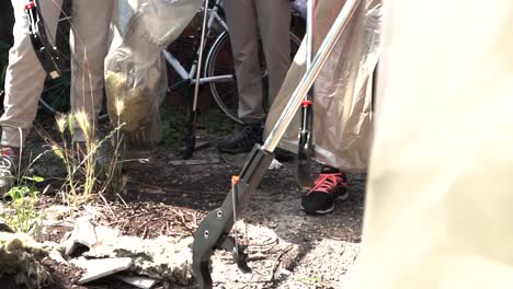 People-collecting-garbage-wusing-trash-pickers-in-Milan-Italy-suburbs