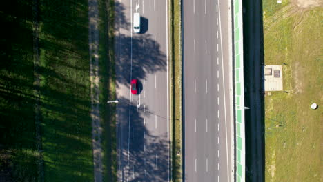 Luftaufnahme-Von-Oben-Nach-Unten---Schnell-Fahrende-Straße-Mit-Rasenden-Autos---Ein-Pfeil,-Der-Das-Ende-Der-Fahrbahn-Anzeigt---Lärmschutzwände-In-Der-Nähe-Der-Straße---Bäume-In-Der-Nähe-Der-Fahrbahn