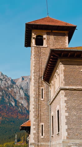 amazing brick castle at the backdrop of mountains. beautiful sunny autumn day near the old mansion. low angle view. vertical video