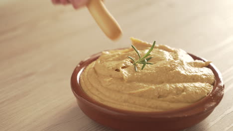 dipping a chip into hummus with rosemary