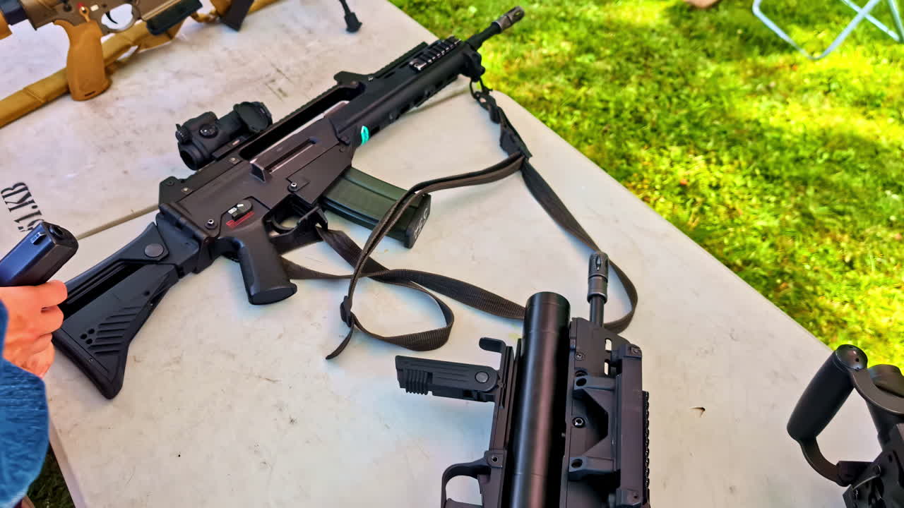 Tactical rifles displayed on white table during outdoor military exhibition event