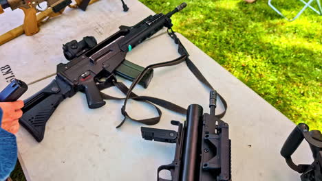 tactical rifles displayed on white table during outdoor military exhibition event