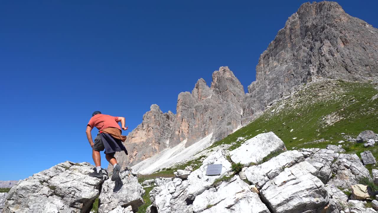 Turista in equilibrio su una formazione rocciosa vicino alle Tre Cime di Lavaredo, Dolomiti, Italia