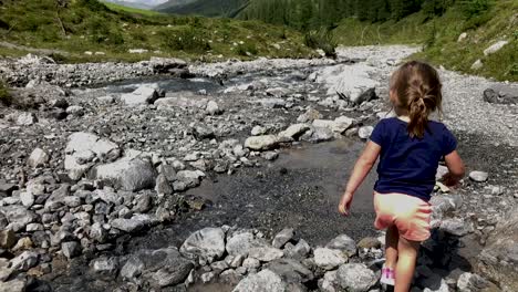 cute little girl having fun playing at the water of a mountain river