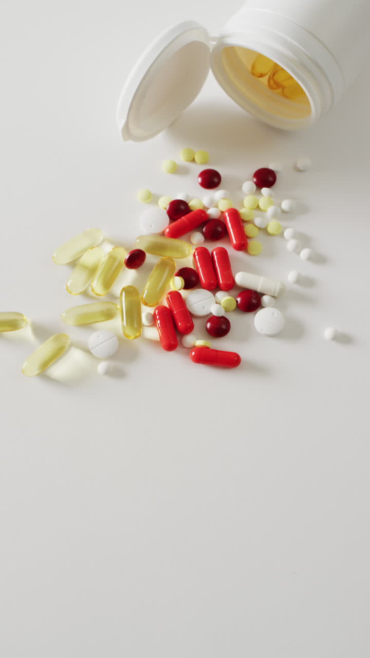 vídeo vertical de una caja de pastillas abierta con cápsulas, pastillas y comprimidos sobre un fondo blanco con espacio para copiar