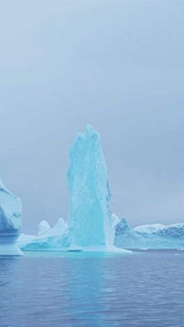 big iceberg ice formation in ocean sea water, large amazing shapes bizarre icebergs in antarctica scenery vertical video for social media, instagram reels and tiktok, antarctic peninsula landscape