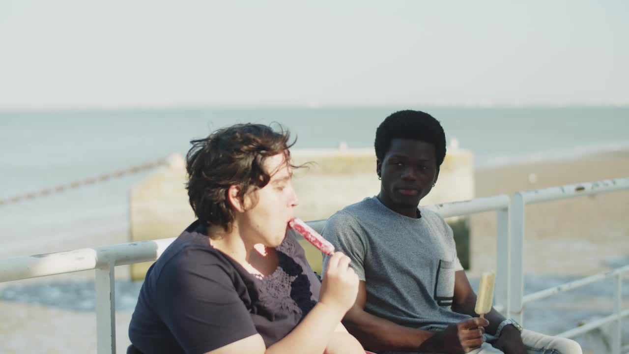 una joven pareja feliz con discapacidad comiendo helado en el muelle