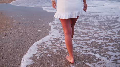 Closeup of a Woman Legs Walking Barefoot on Wet Sand with Sunset Reflections. Close-up of a woman legs walking barefoot on wet sand with sunset reflections