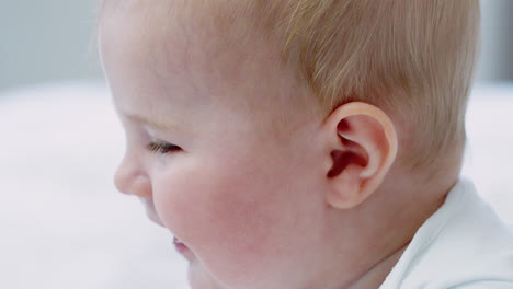 close up of happy baby boy sitting on parents bed