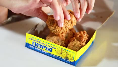 hands sharing deep-fried bananas from a box