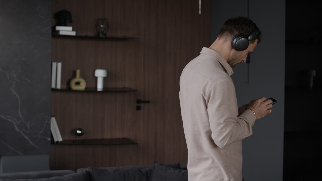 Man with headphones using a smartphone indoors