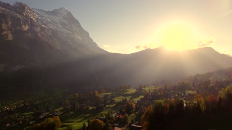 aerial drone footage pushing in right to left over grindelwald village with spectacular sunset view of eiger north face, switzerland