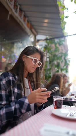 woman using phone in outdoor cafe