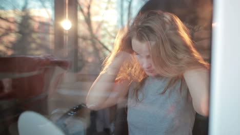 Through-the-window-portrait-of-girl-enjoying-her-hair