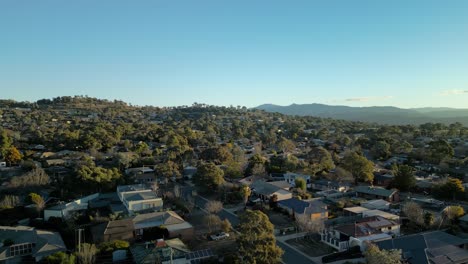 drone rises above rivett, revealing rooftops, streets, and the full scale of this leafy suburb in golden afternoon light