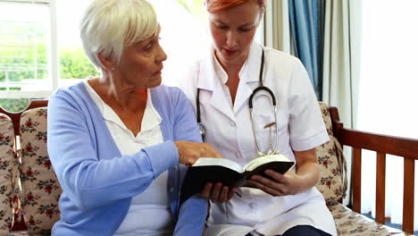 senior woman and nurse reading a book together