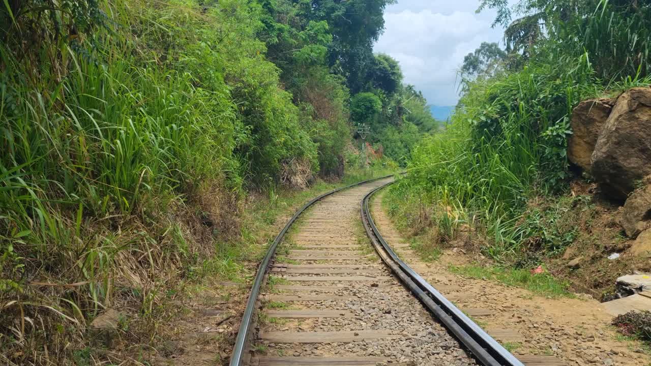 Tampilan yang mengungkap jalur kereta api Badulla–Colombo yang kosong dekat Ella, Sri Lanka, saat meliuk-liuk melalui dataran tinggi berkabut dan hutan tropis yang lebat