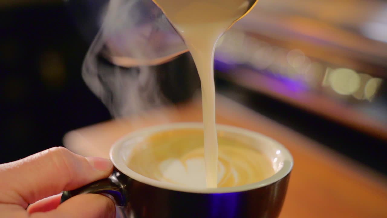 Making a foam heart on a coffee cup slow motion.