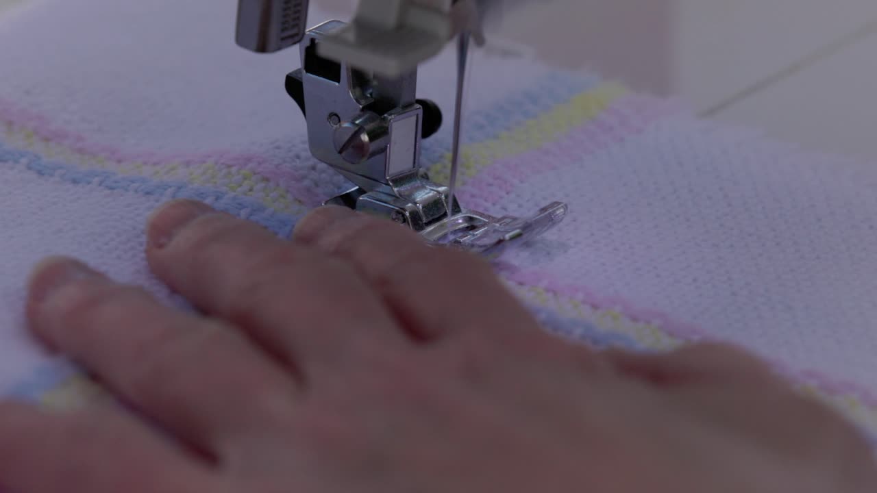 close-up shot of a sewing amchine stitching around a border on a baby blanket