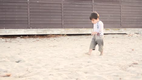 medium shot of adorable little boy with muddy hands toddling on the sandy beach in malta