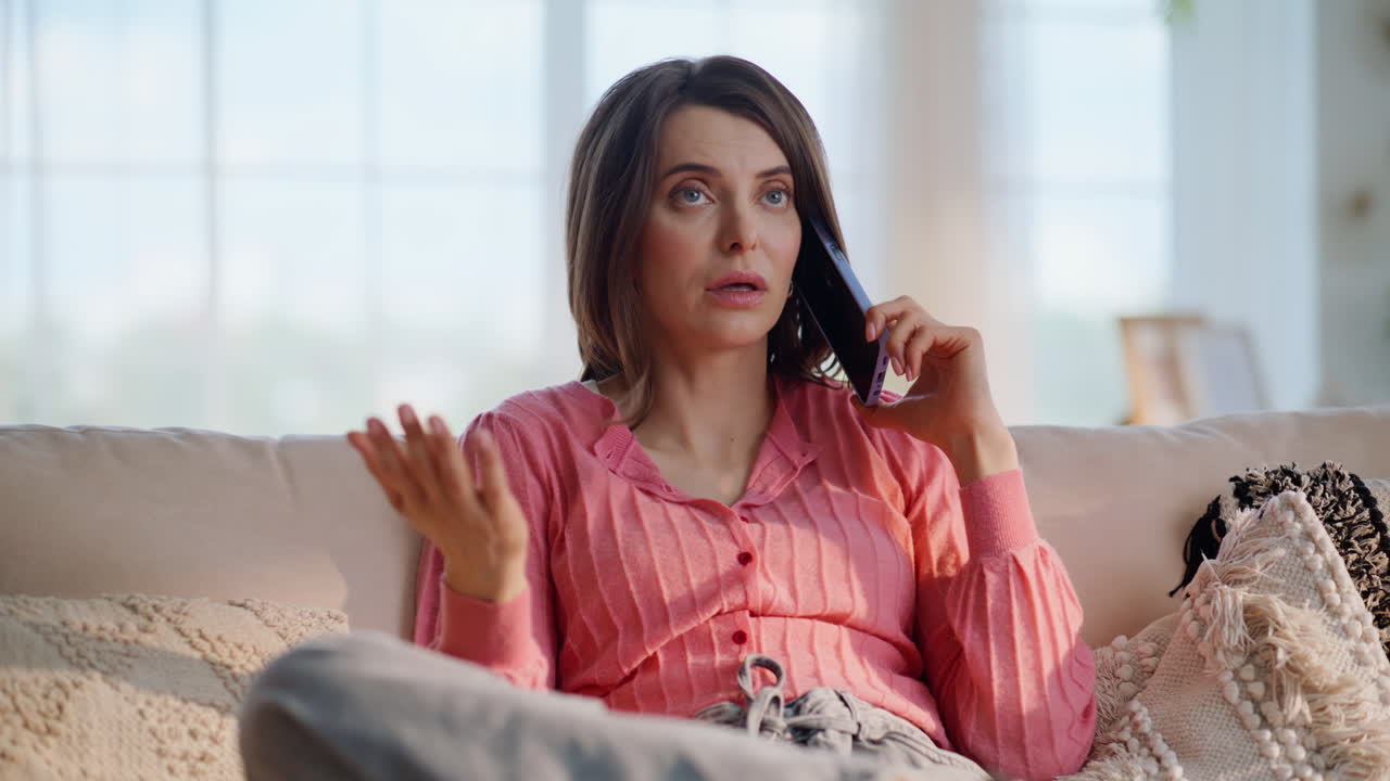 Sad housewife calling mobile phone sitting modern apartment living room closeup