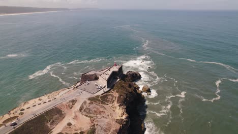 órbita-Aérea-Alrededor-Del-Famoso-Faro-En-La-Costa-Rocosa,-Océano-Atlántico---Nazar?