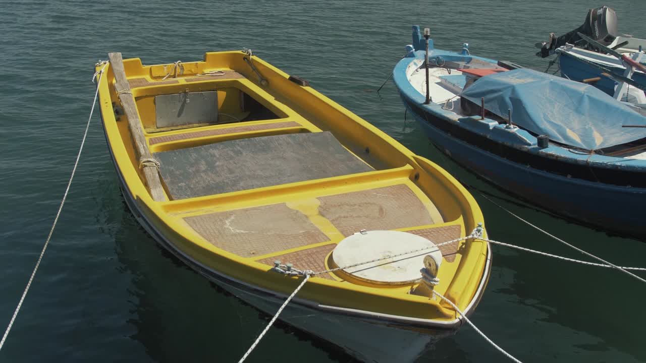 pequeño barco de plástico amarillo brillante amarrado en paneles de madera contrachapada del puerto costero en cámara lenta
